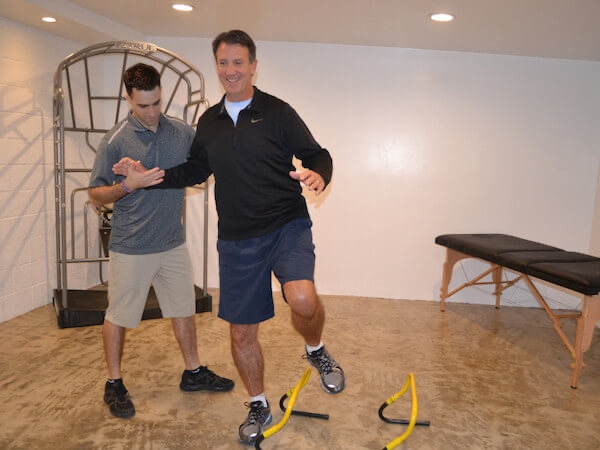 Physical therapist helping a man stand on a single foot with stability