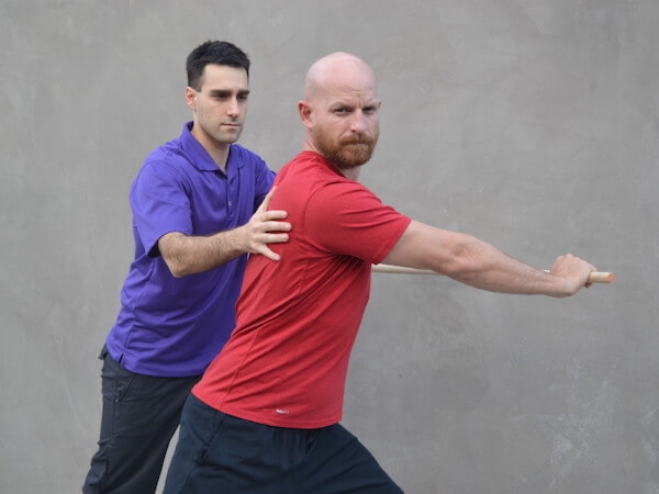 Physical therapist aiding a man turning his shoulders with stability