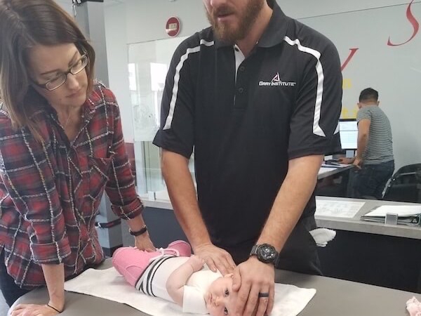 Male professional checking a young infant for torticollis