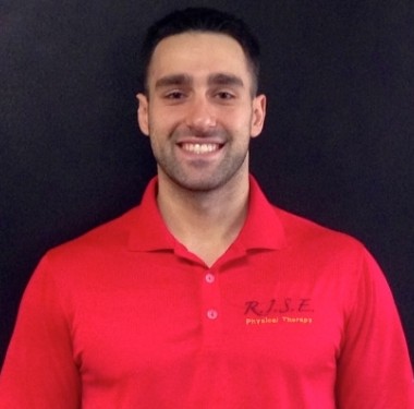 Man with facial hair and red shirt smiling