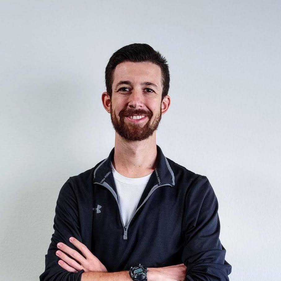 Man with facial hair and red shirt smiling